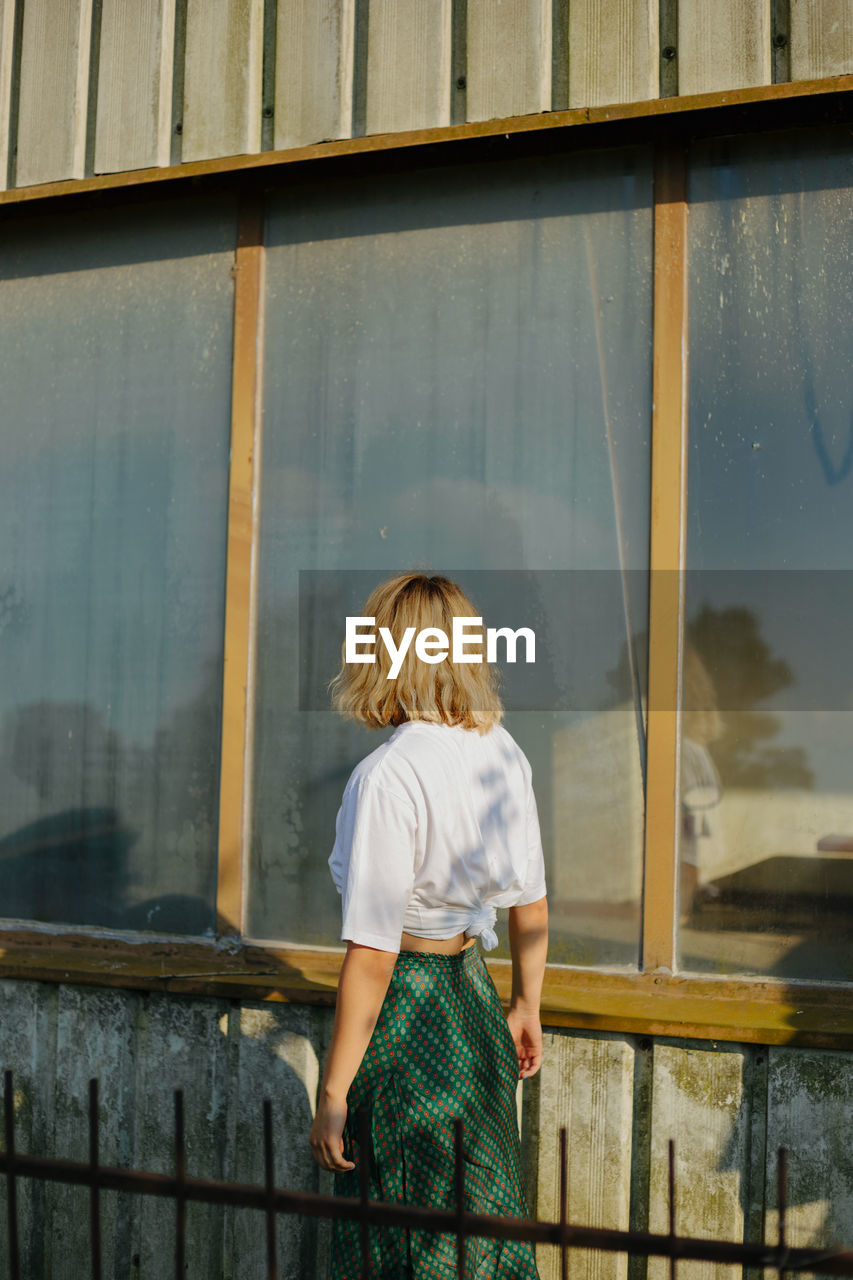 Rear view of woman standing by window