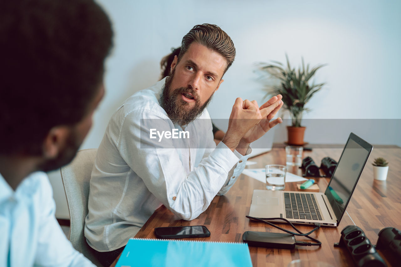 Man talking with faceless coworker in office