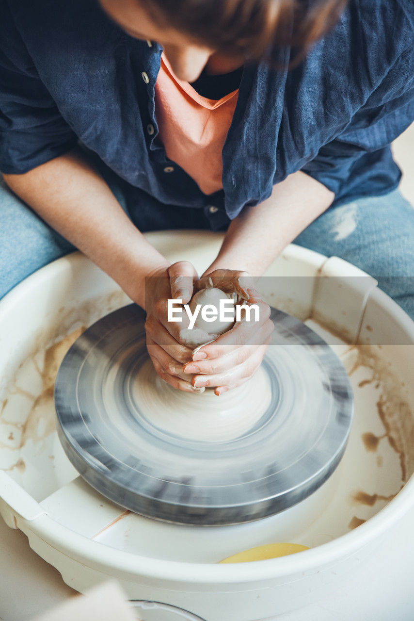 A woman ceramist at a pottery wheel in a workshop