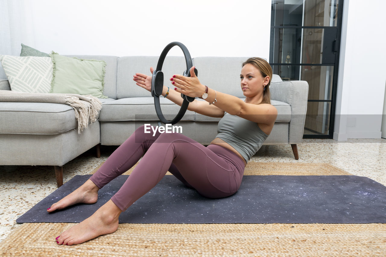 Young woman using pilates ring at home