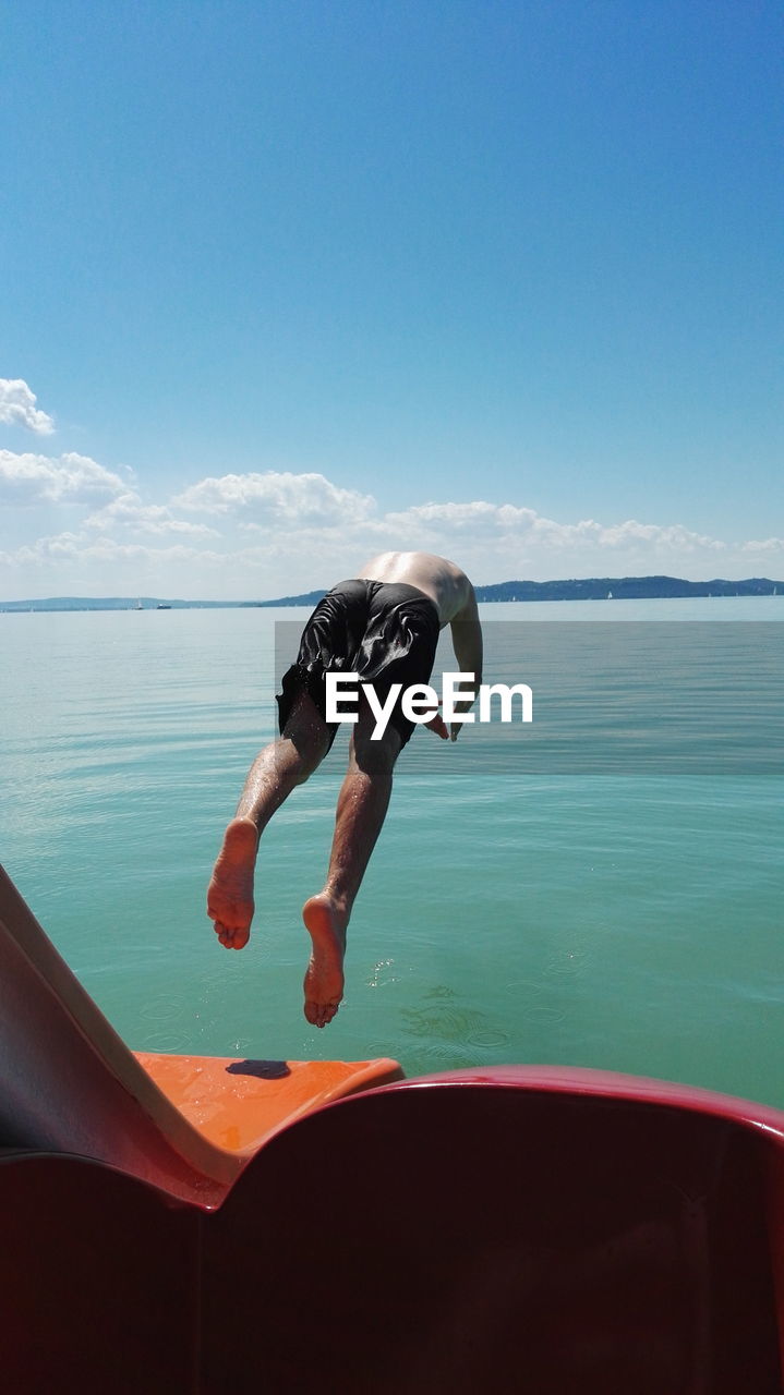 MAN JUMPING IN SEA AGAINST SKY