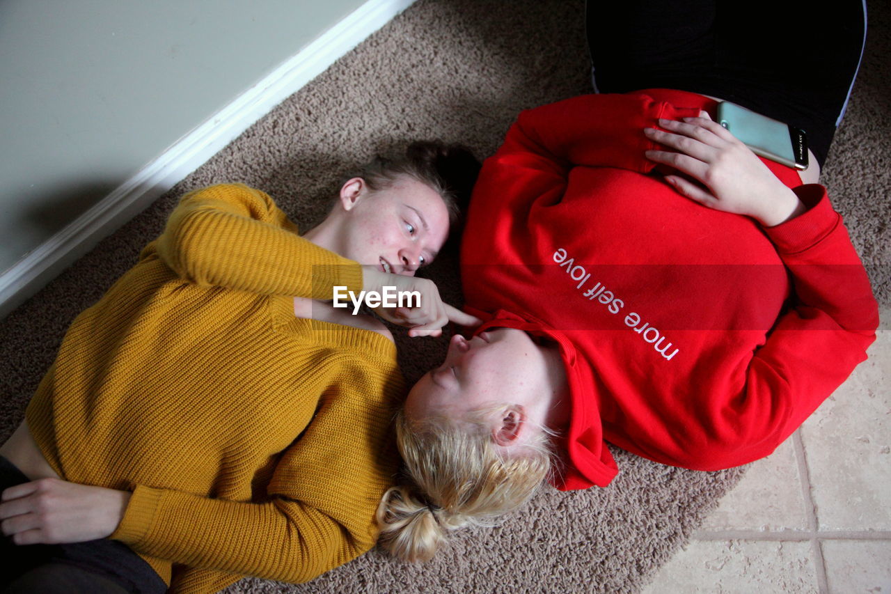 High angle view of young lesbian couple lying on rug at home