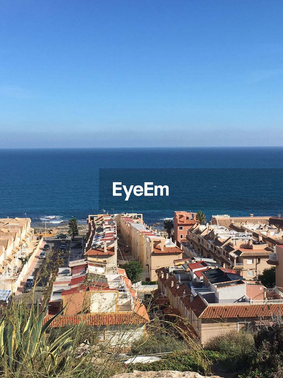 High angle view of cityscape by sea against clear sky