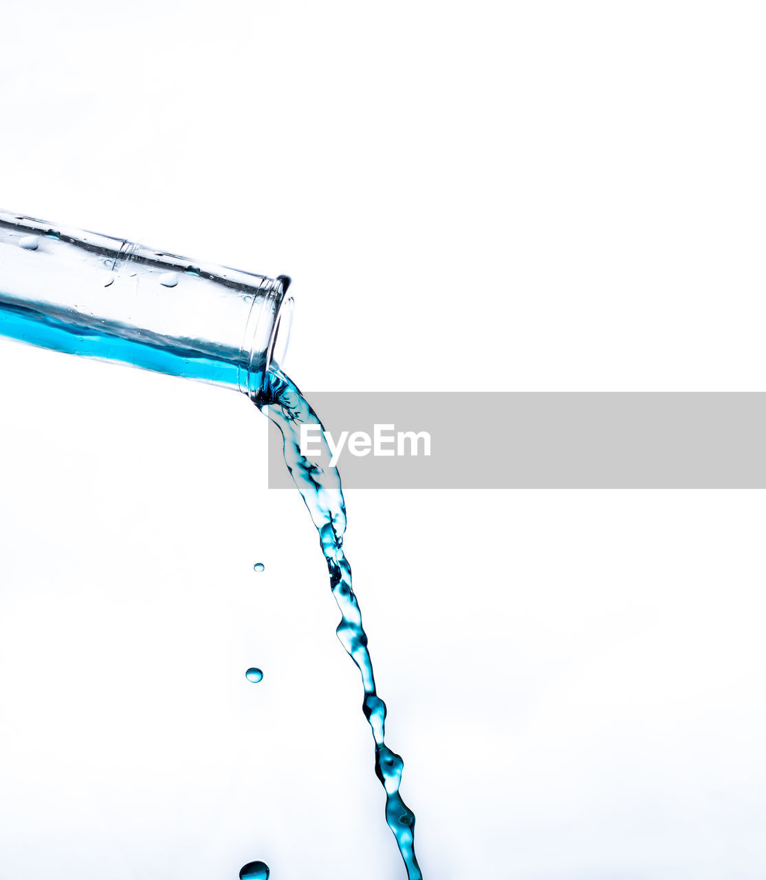 Close-up of blue drink being poured against white background