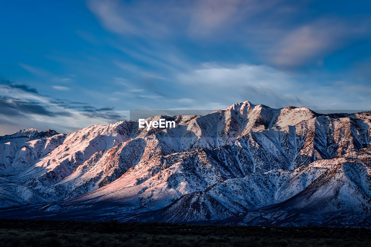 Early morning blue sky with white clouds above snowy eastern sierra nevada mountains