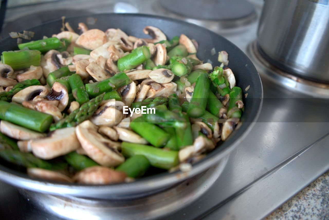 High angle view of mushrooms and asparagus in pan on stove 