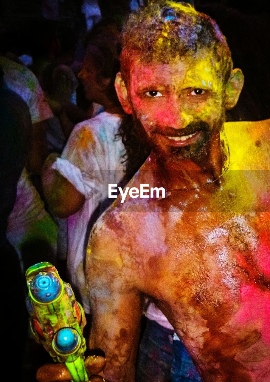 CLOSE-UP PORTRAIT OF MAN WITH MULTI COLORED LIGHT PAINTING