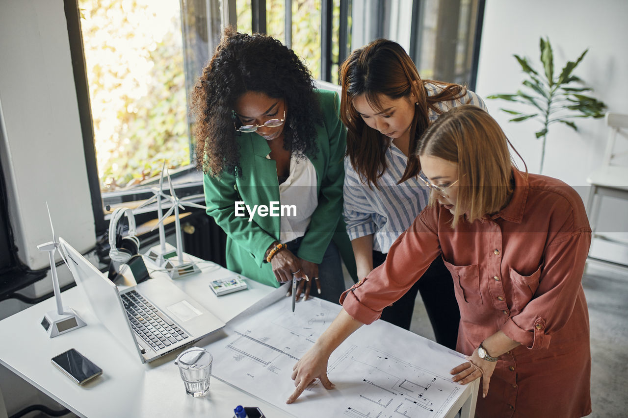 Businesswomen having a meeting in office with wind turbine models on table