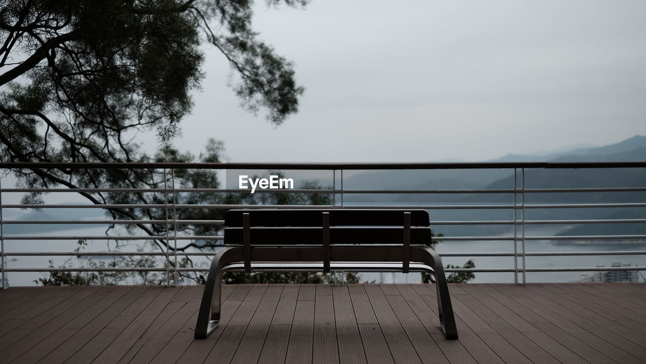 seat, nature, sky, water, tree, railing, tranquility, bench, no people, absence, wood, beauty in nature, tranquil scene, plant, relaxation, day, scenics - nature, empty, outdoors, architecture, chair, sea, reflection, table, furniture, built structure