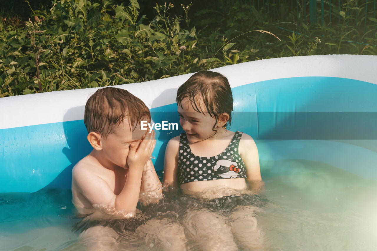 Cheerful happy children in the pool. friends spend summer leisure together on a hot day