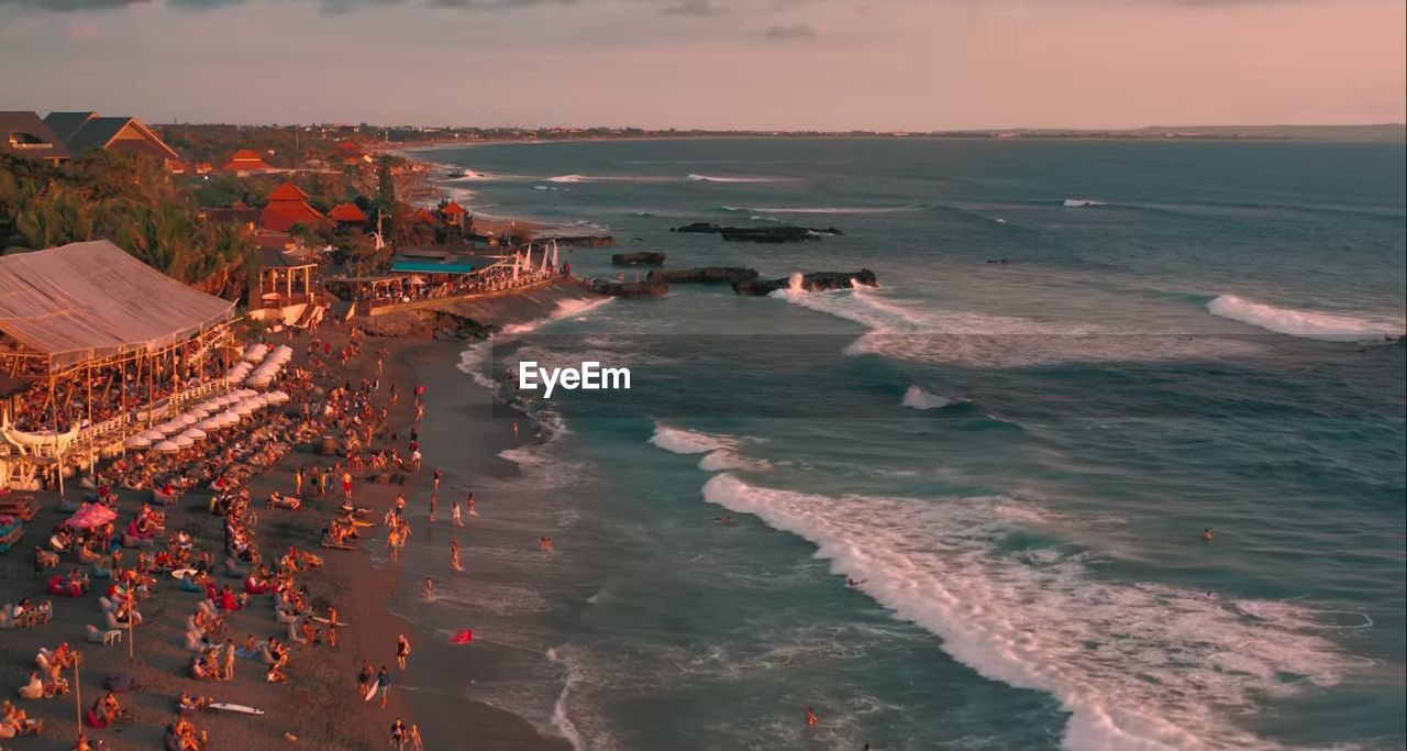 HIGH ANGLE VIEW OF CROWD AT BEACH AGAINST SKY