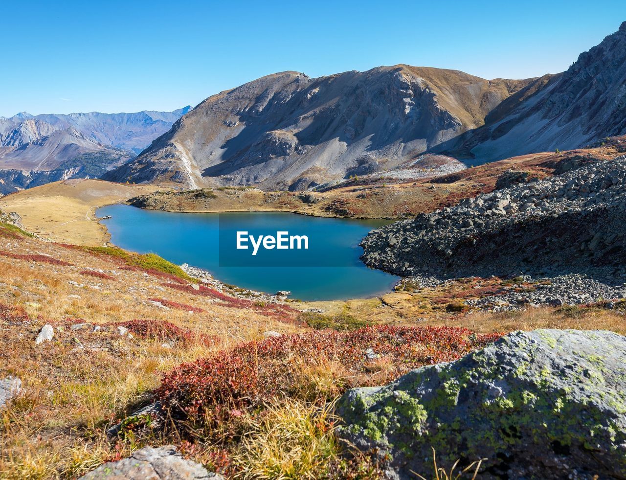 Scenic view of lake and mountains against clear blue sky