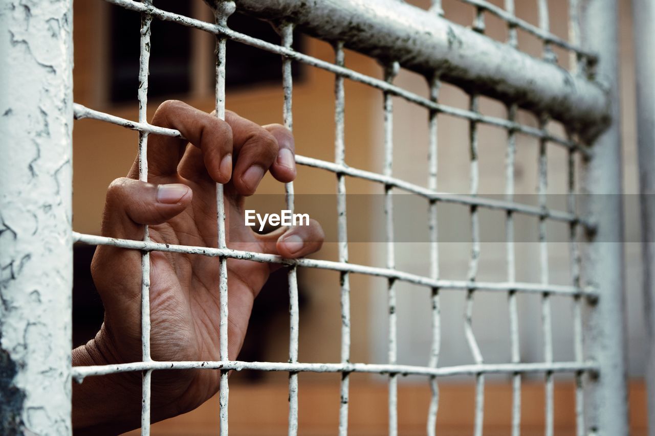 Cropped hand holding metal grate