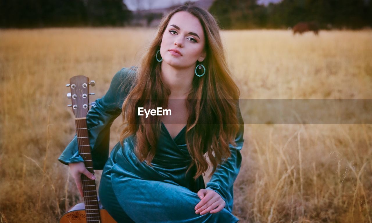 Portrait of beautiful young woman sitting on field