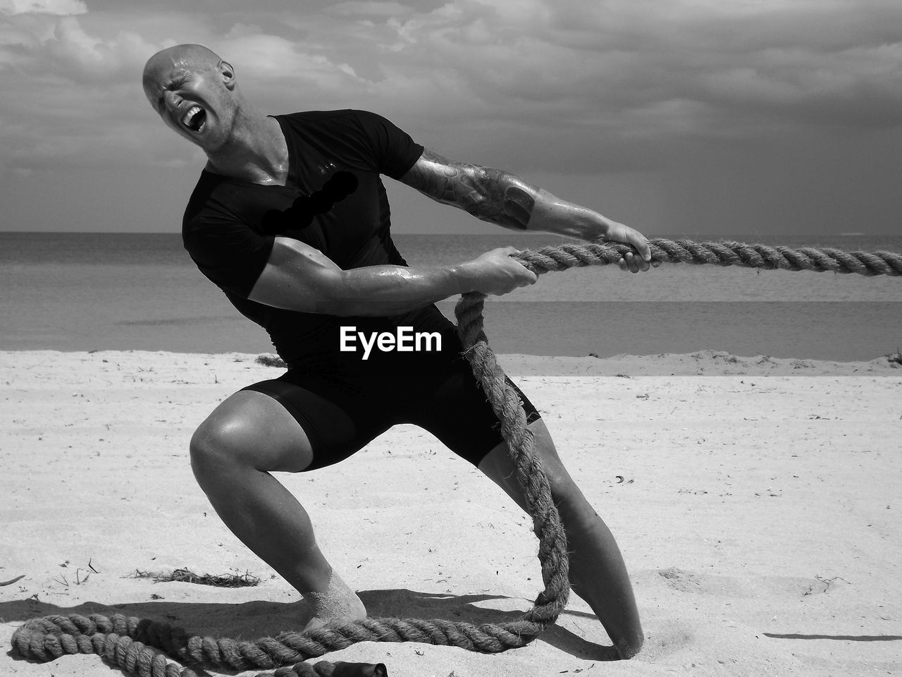 Full length of man pulling rope while standing on sand at beach