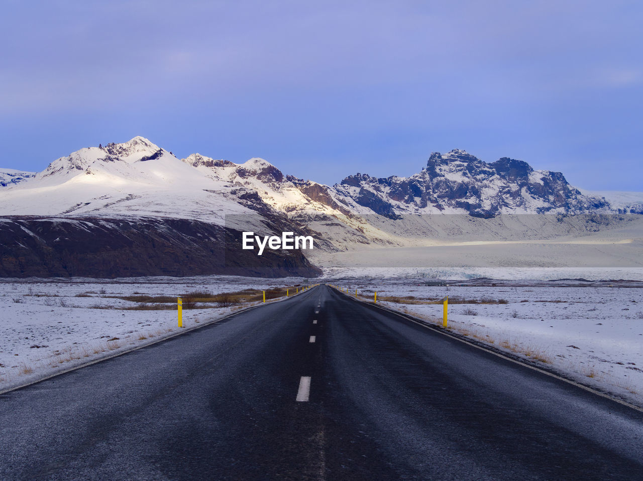 Road amidst snowcapped mountains against sky