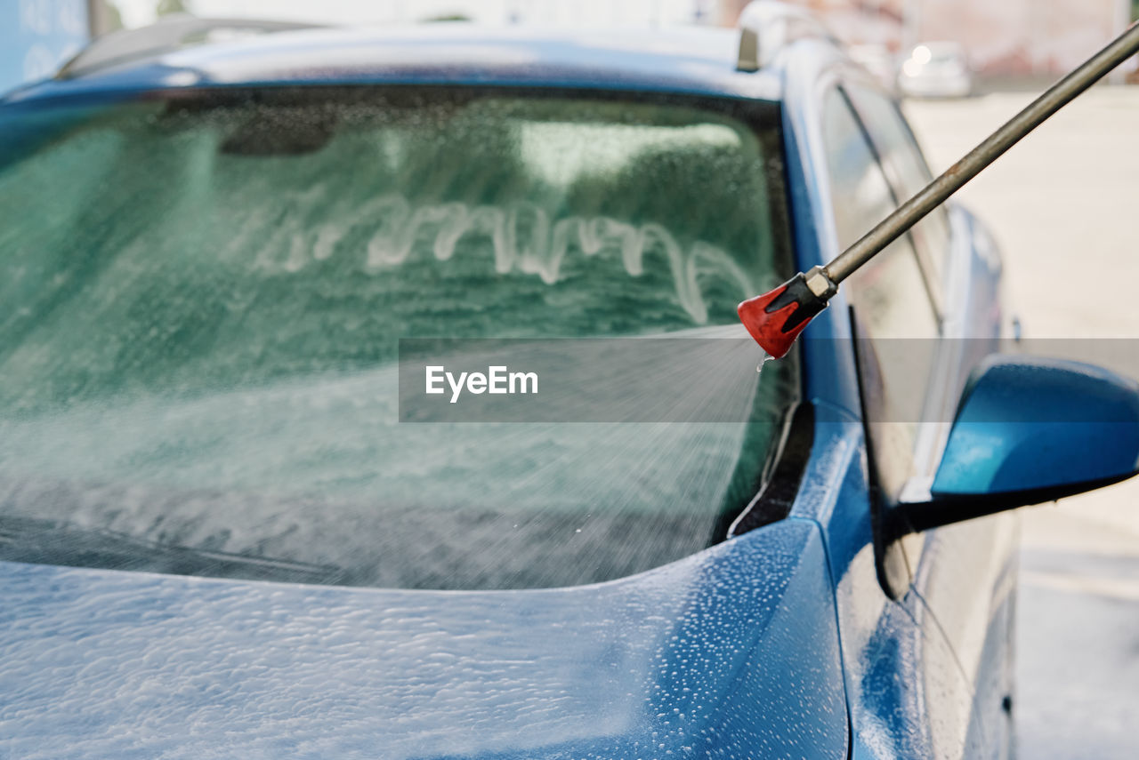 Cleaning car with high pressure water at car wash station