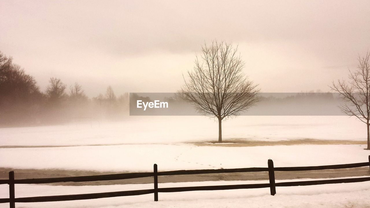 Scenic view of snow covered field against cloudy sky