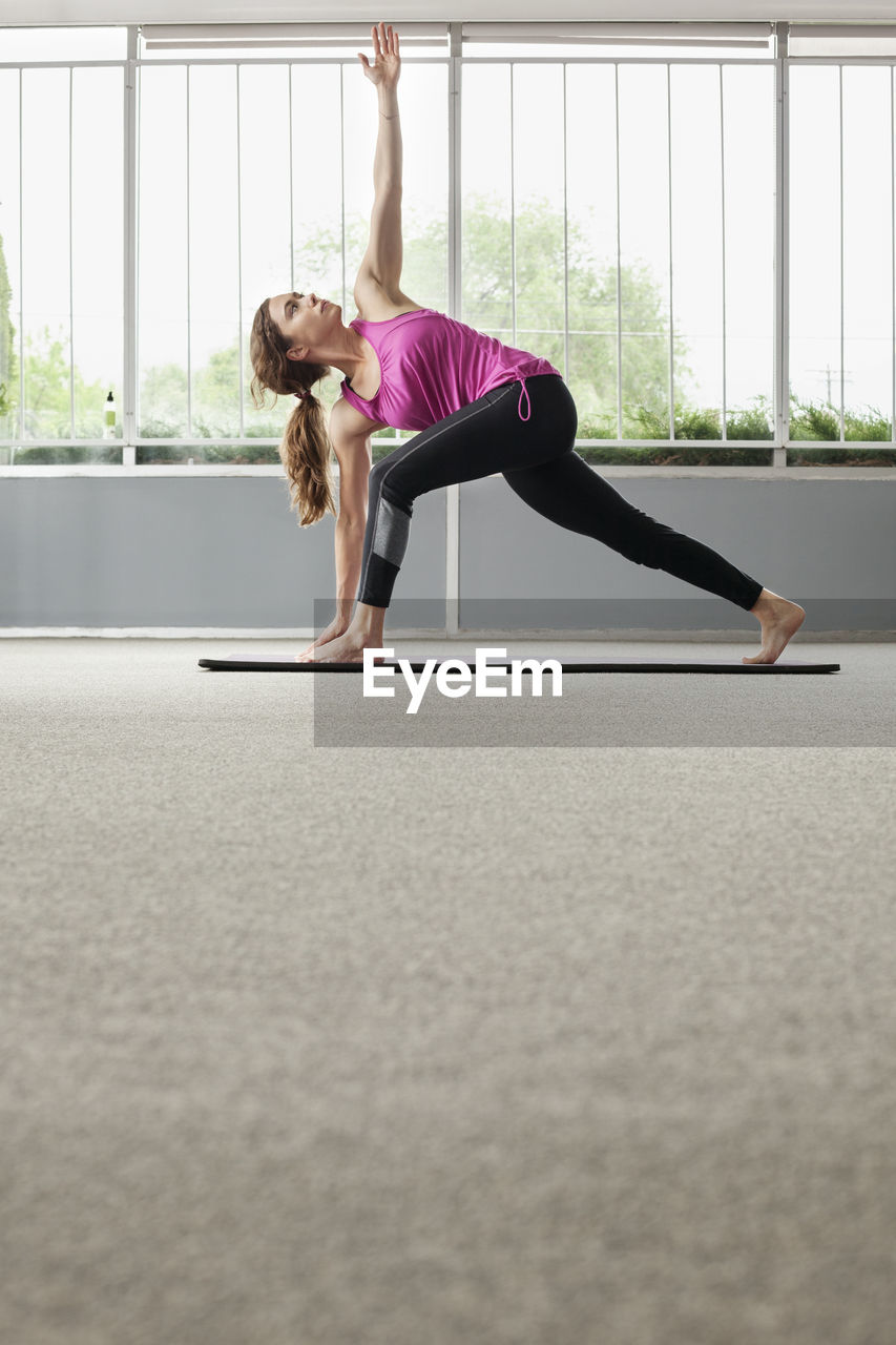 Woman practicing triangle position in gym