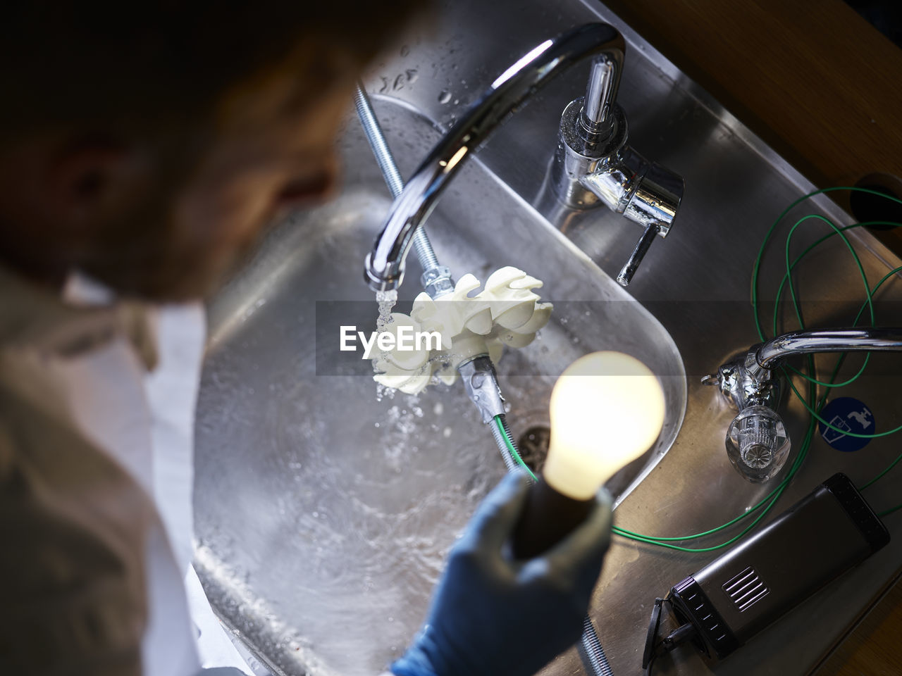 Technician with light bulb and turbine wheel being tested for power generation