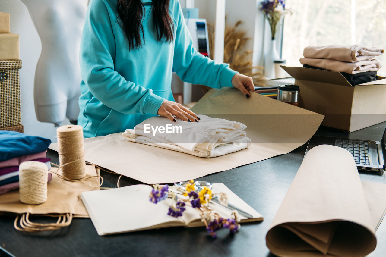 Small business owner woman packs the goods in eco packaging in office, shop.