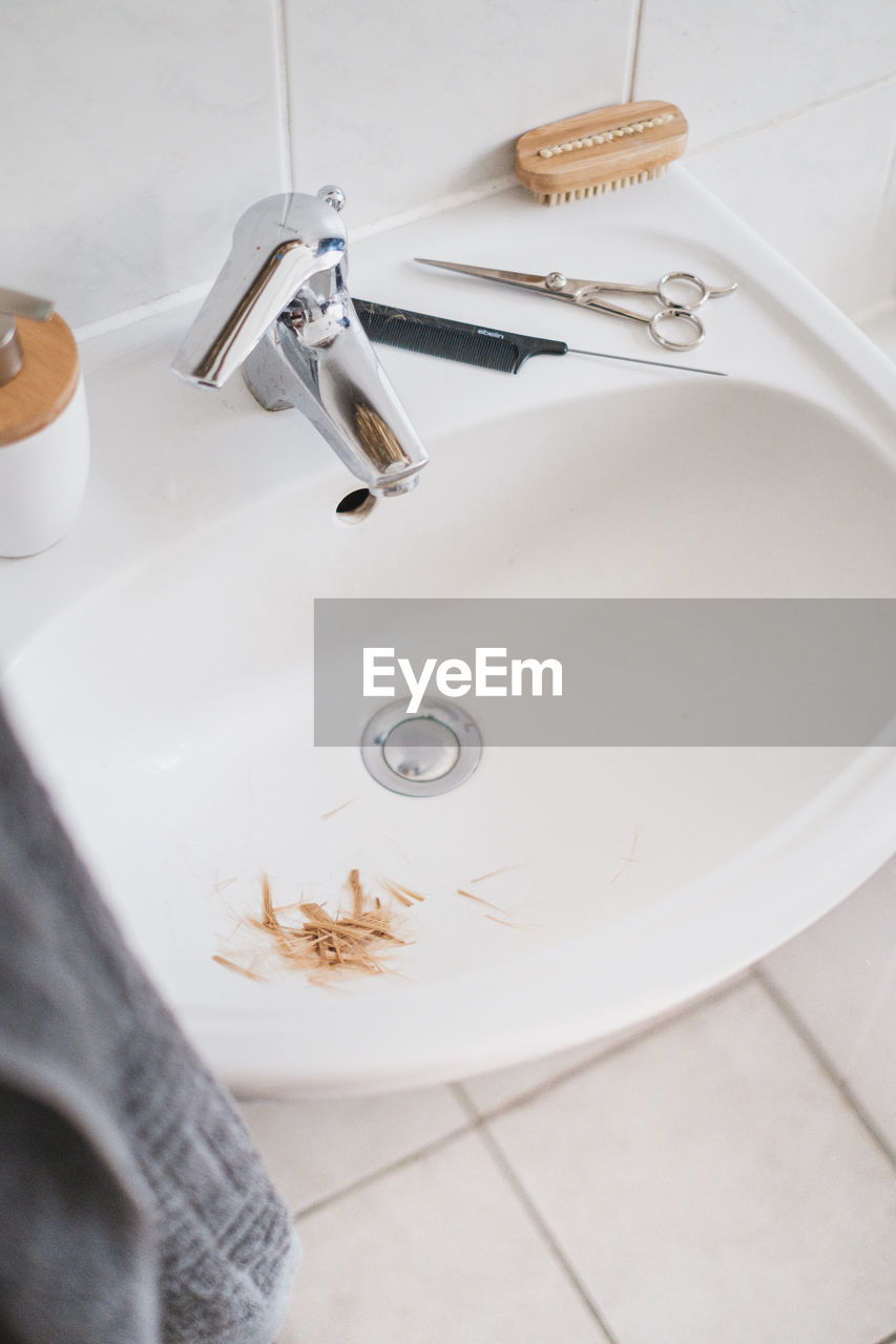 High angle view of faucet and sink in bathroom at home with slices of hair