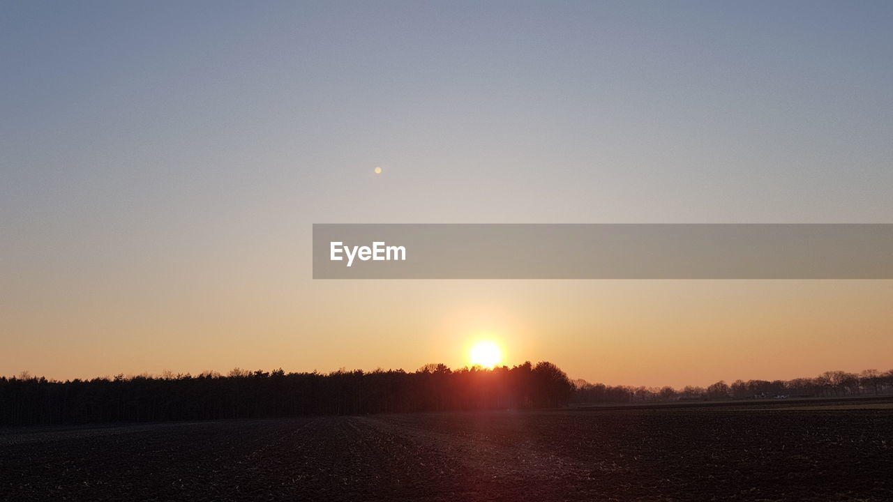 SCENIC VIEW OF SILHOUETTE FIELD AGAINST ORANGE SKY