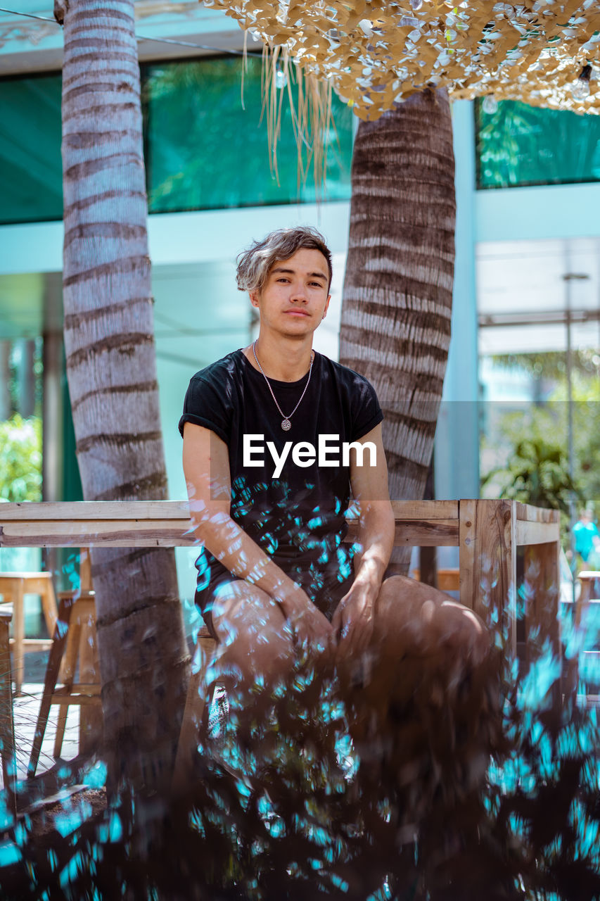 Portrait of young man sitting at a summer style restaurant