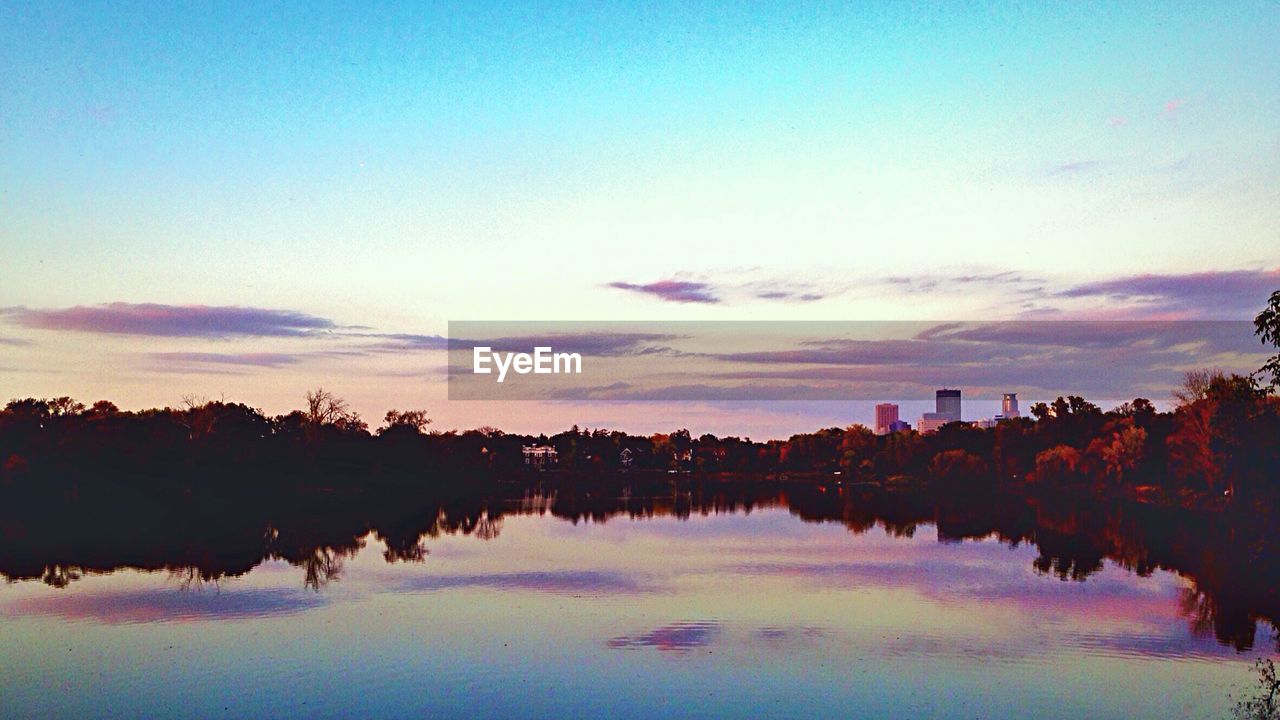 Reflection of trees in lake against blue sky during sunset