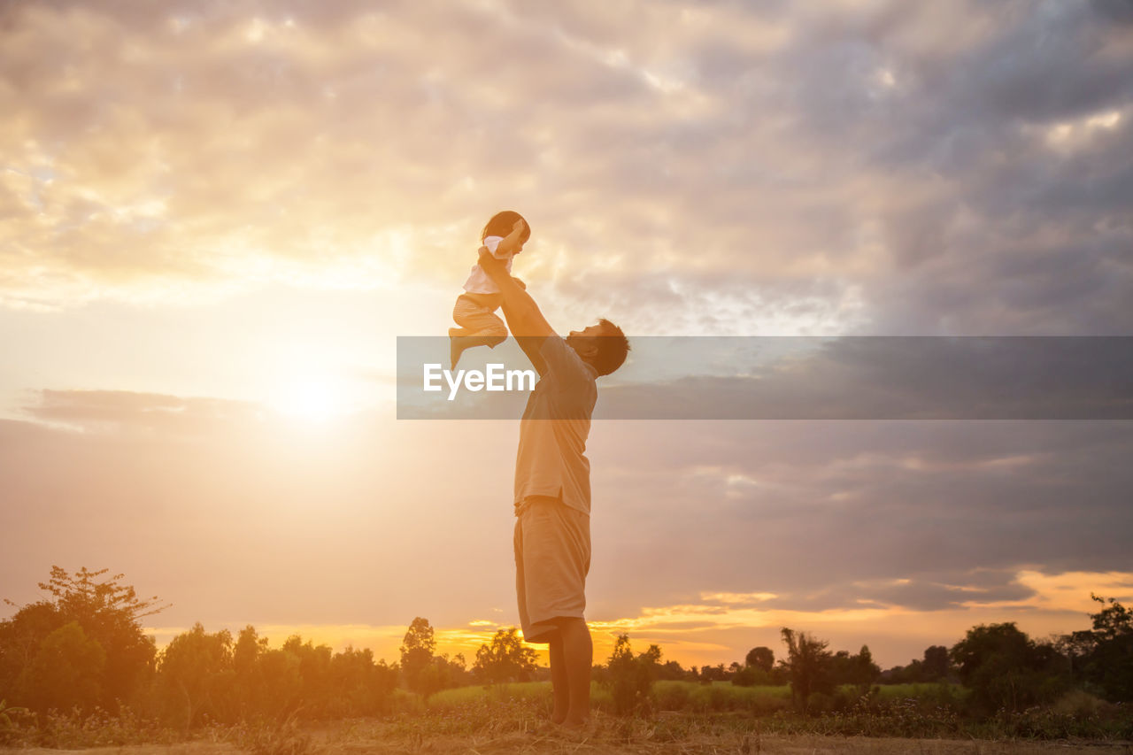 MAN STANDING ON FIELD DURING SUNSET