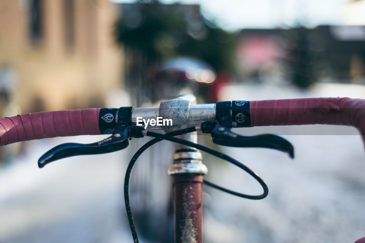 CLOSE-UP OF HAND HOLDING BICYCLE ON METAL