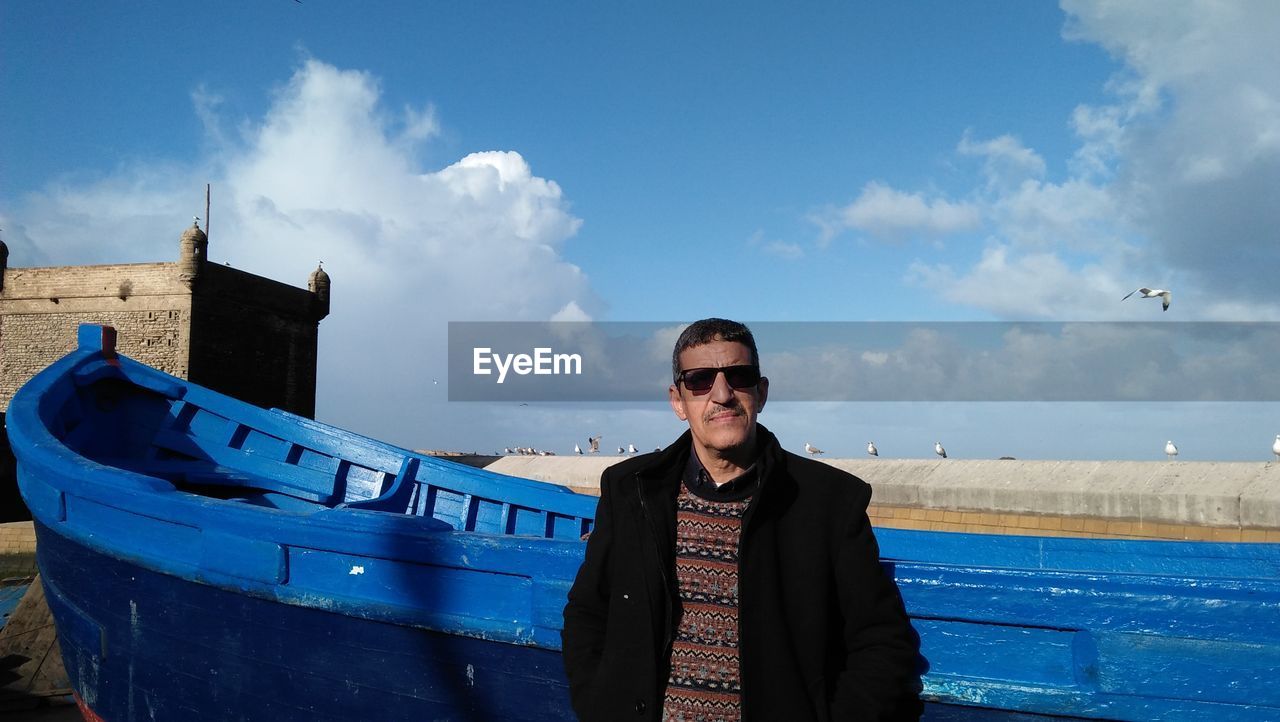 Portrait of man wearing sunglasses standing against sky