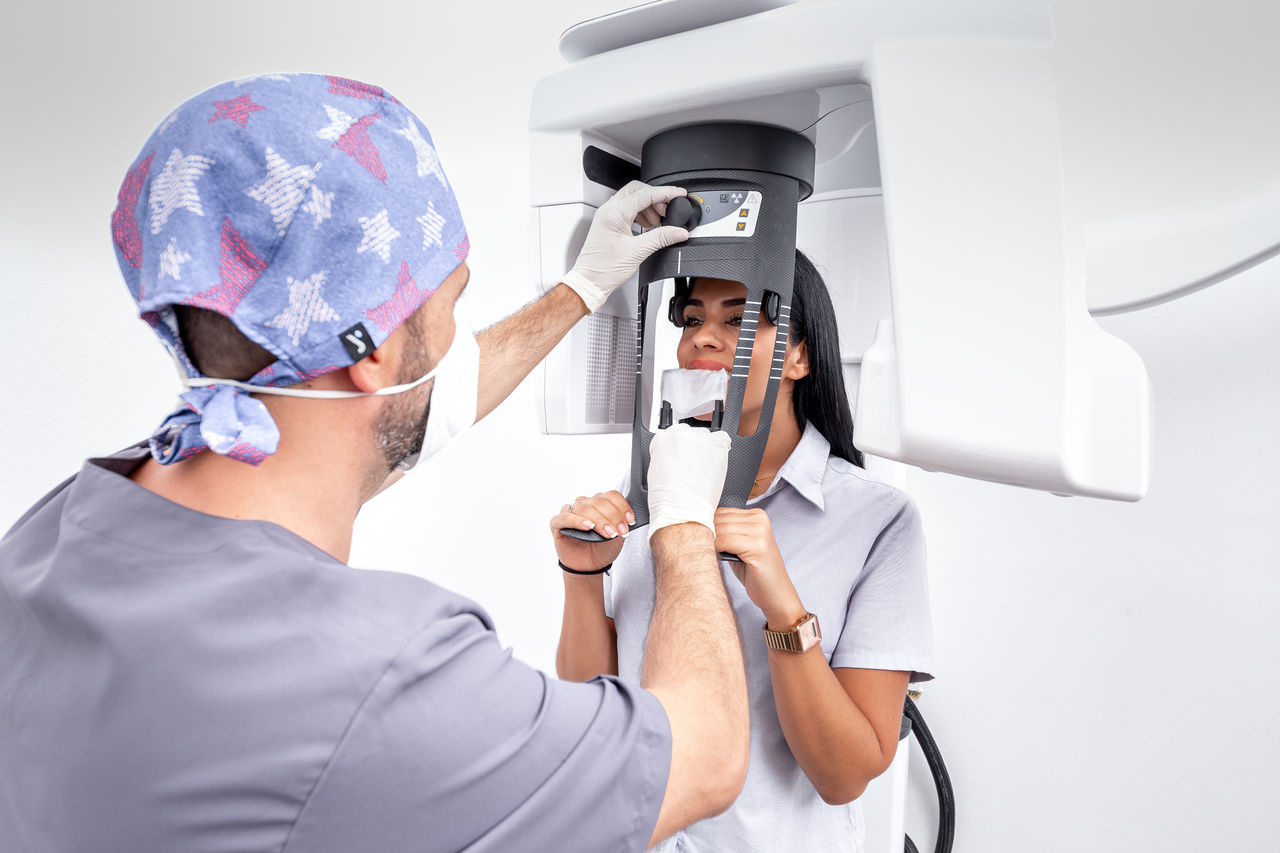 Male dentist adjusting a tooth whitening machine used by a female patient in a dental clinic