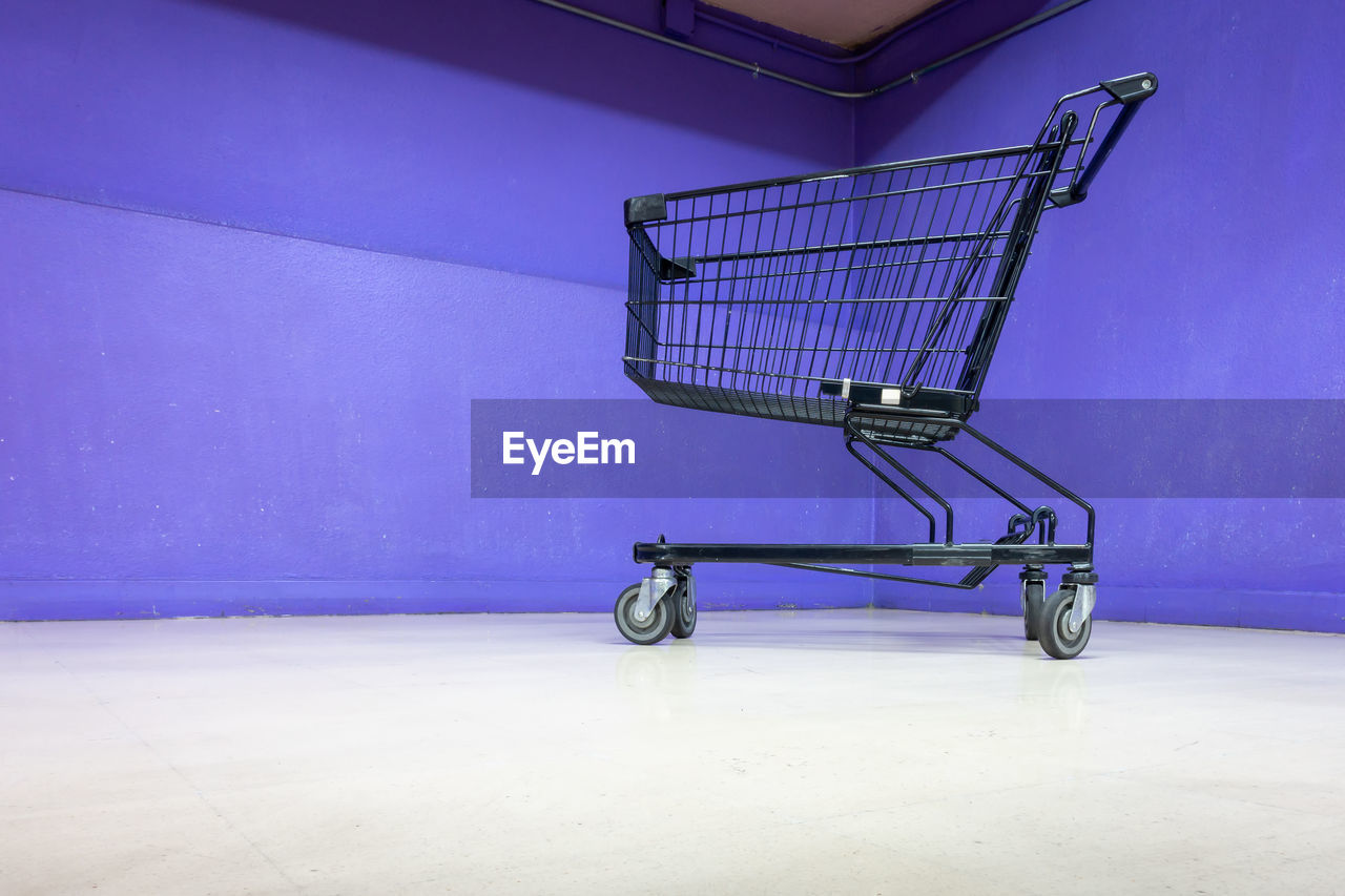 Low angle view of shopping cart against blue wall