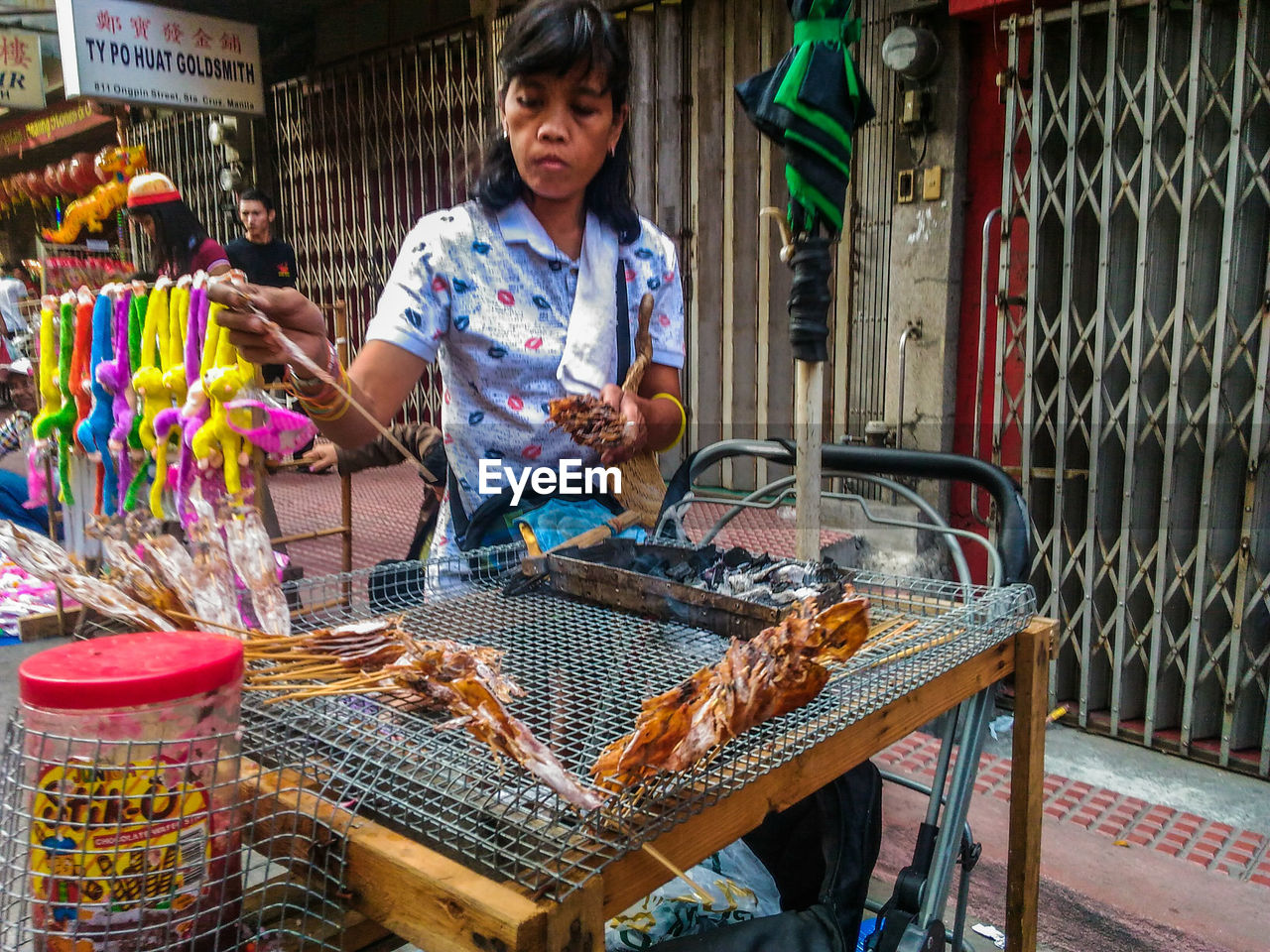 Female vendor with dried calamari for sale at footpath