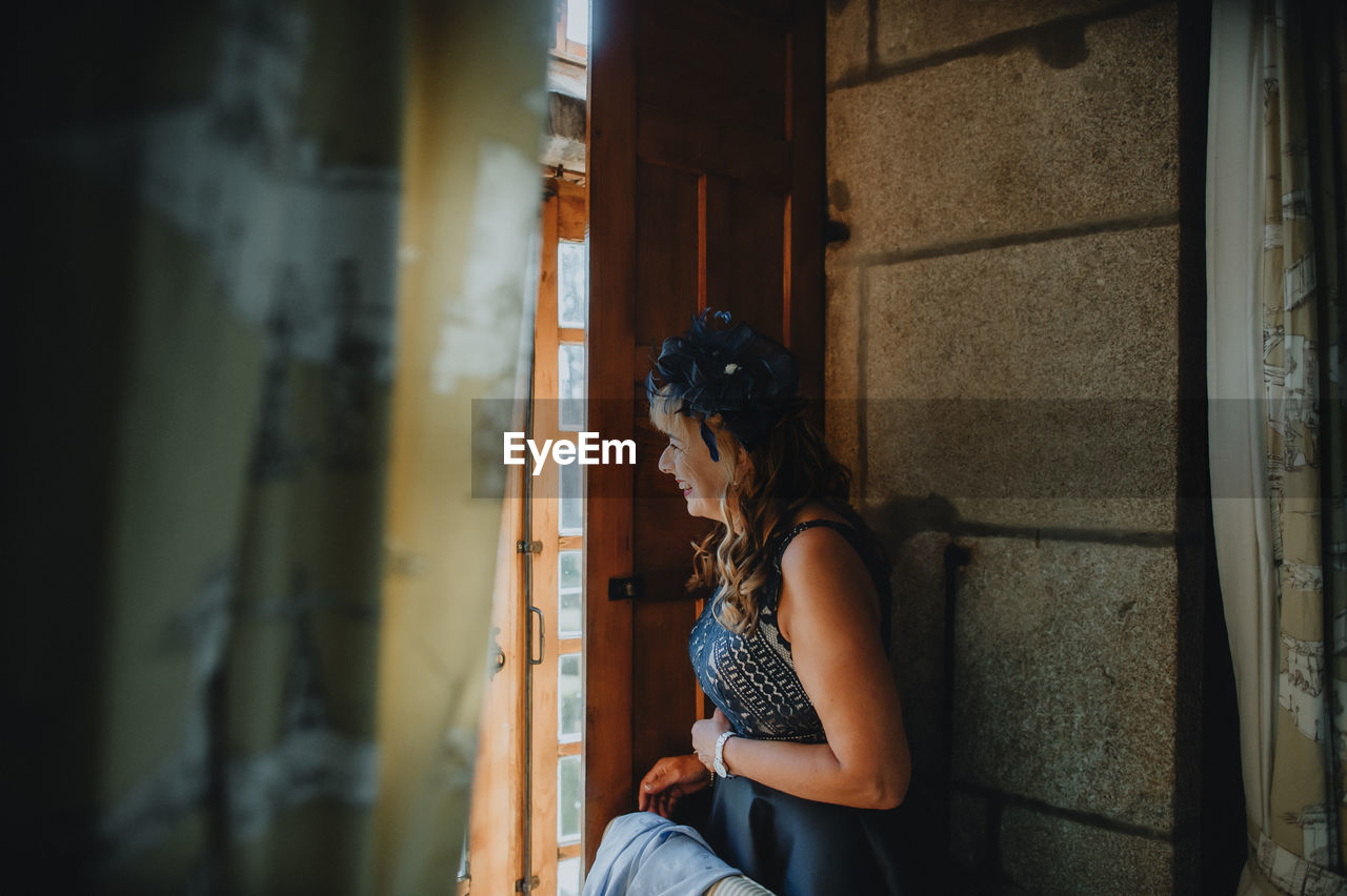 Smiling woman looking away while standing by door