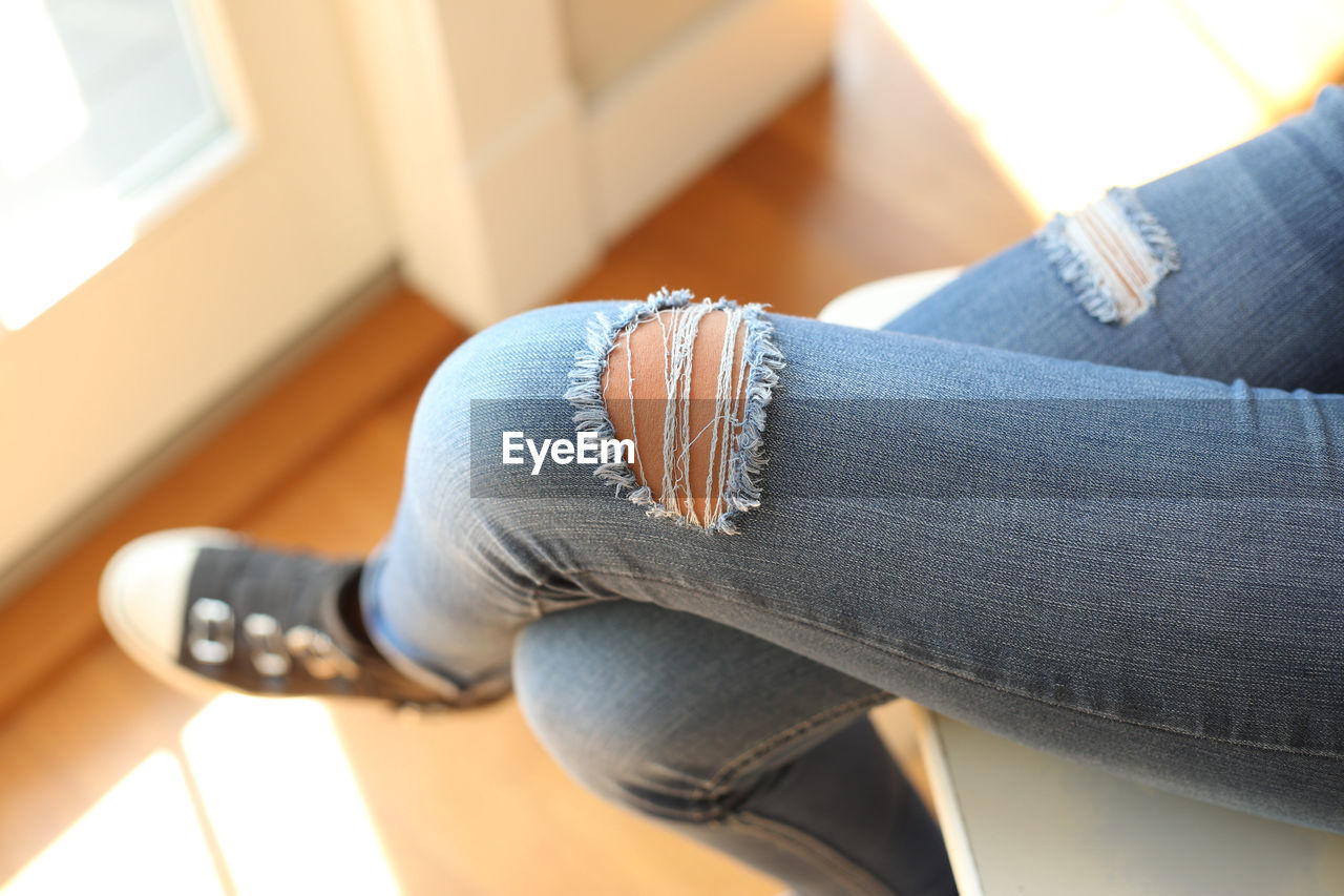 Low section of woman wearing torn jeans