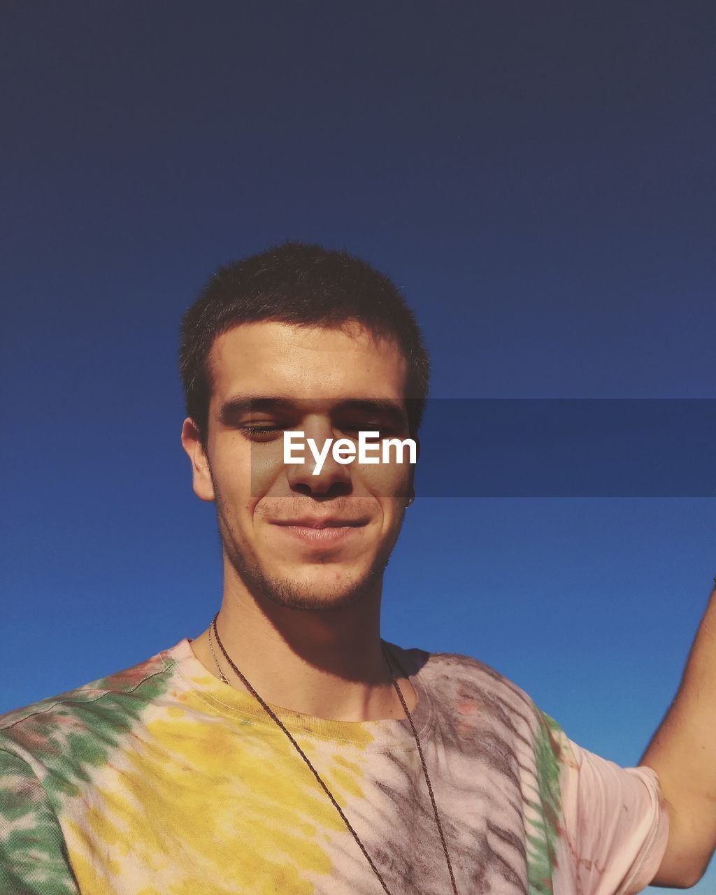  young man standing against blue sky