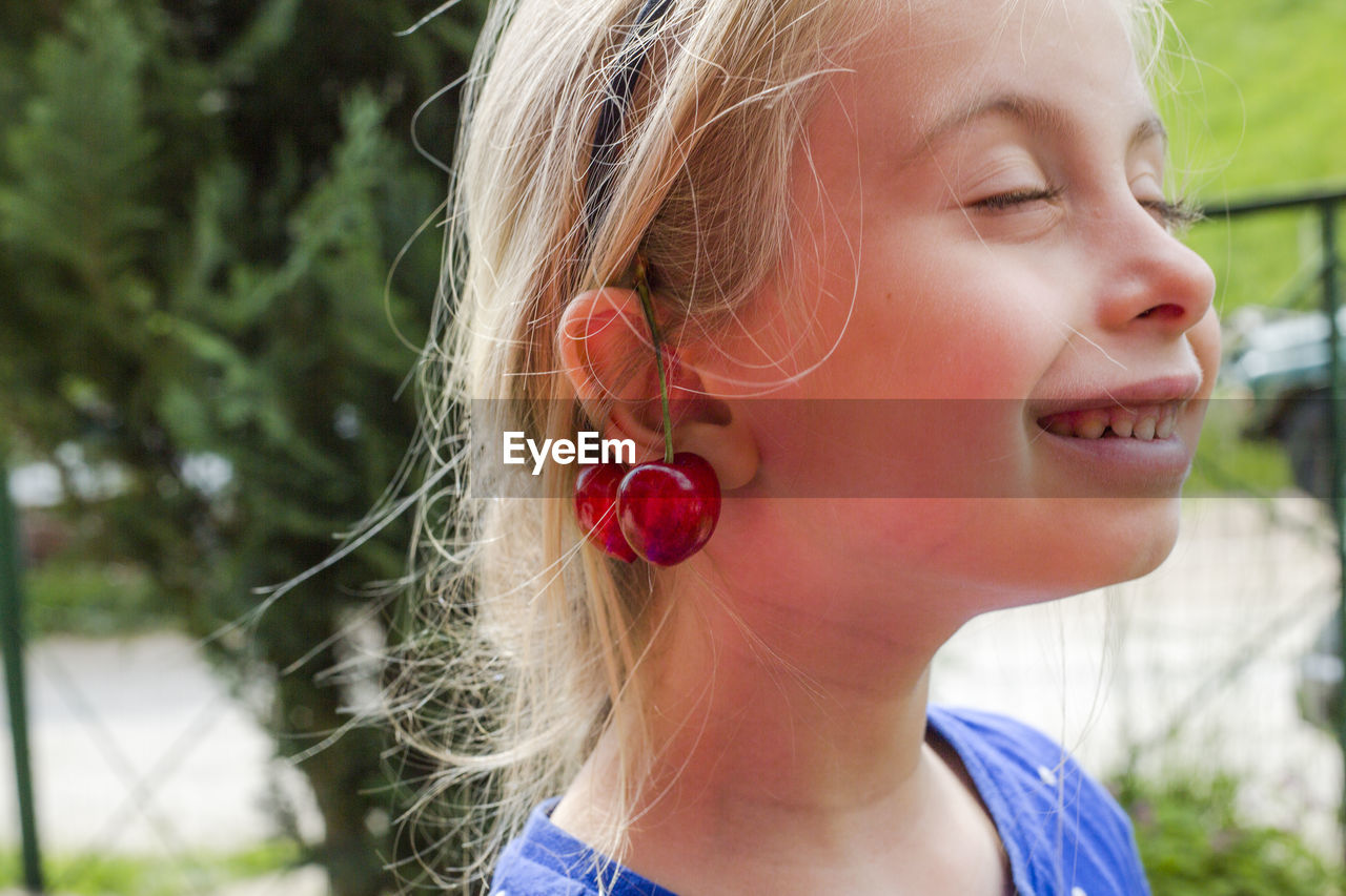 Close-up of cute girl with cherry on ear