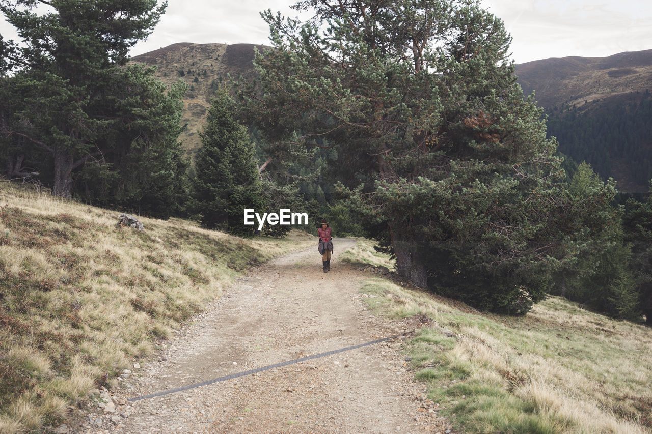 Woman walking dirt road on mountain