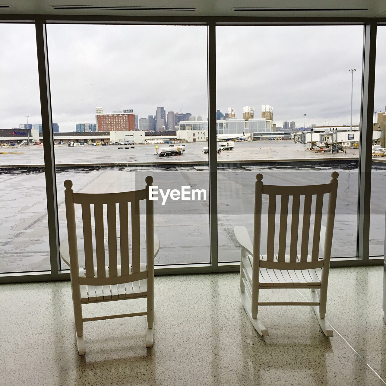 CHAIRS AND TABLE BY RIVER AGAINST CITYSCAPE