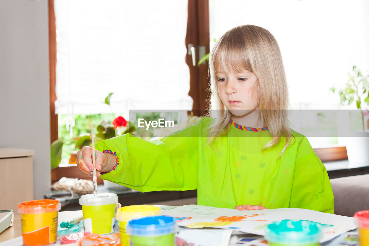 Girl painting on paper while sitting at home