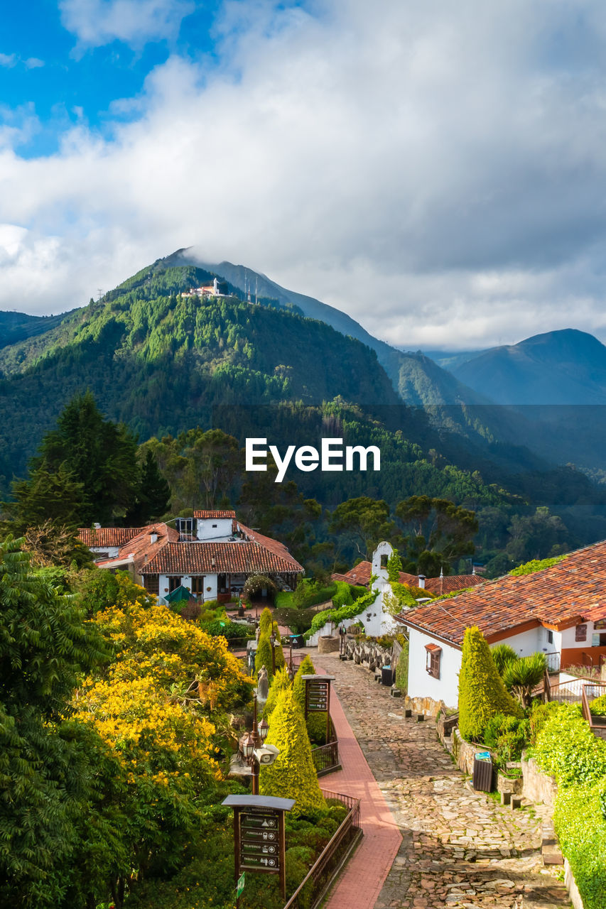 Houses amidst trees and buildings against sky