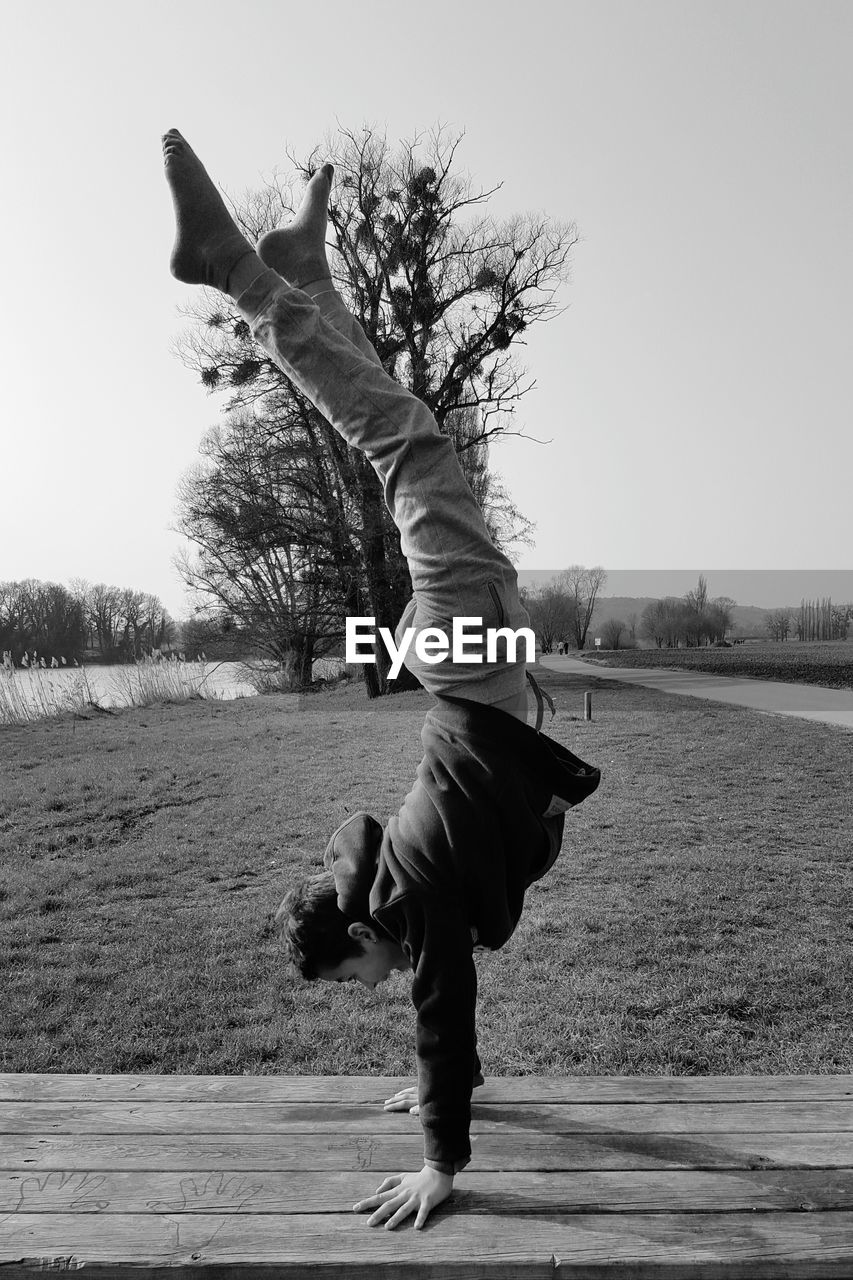 Boy doing handstand on wooden bench