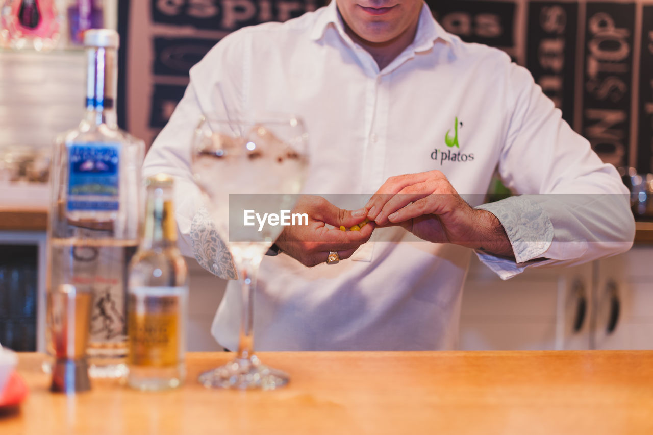 Midsection of bartender preparing drink at counter