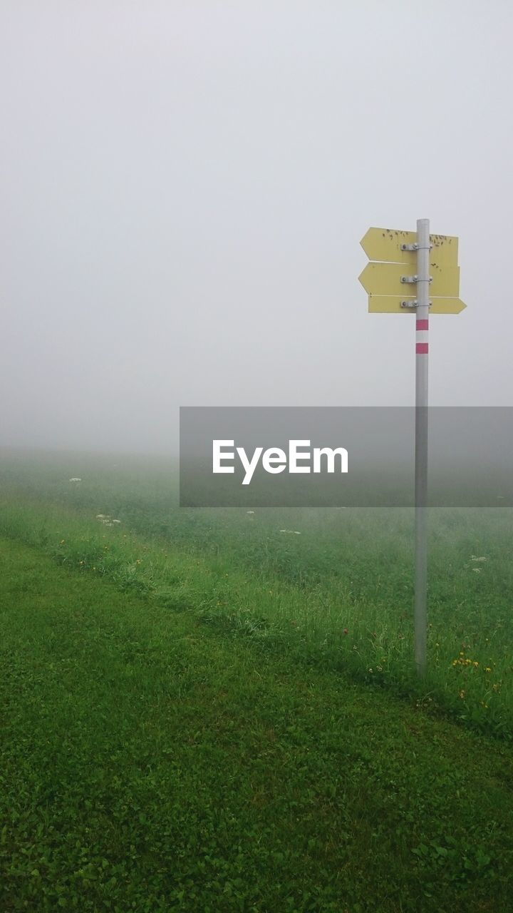 Information sign on grassy field during foggy weather