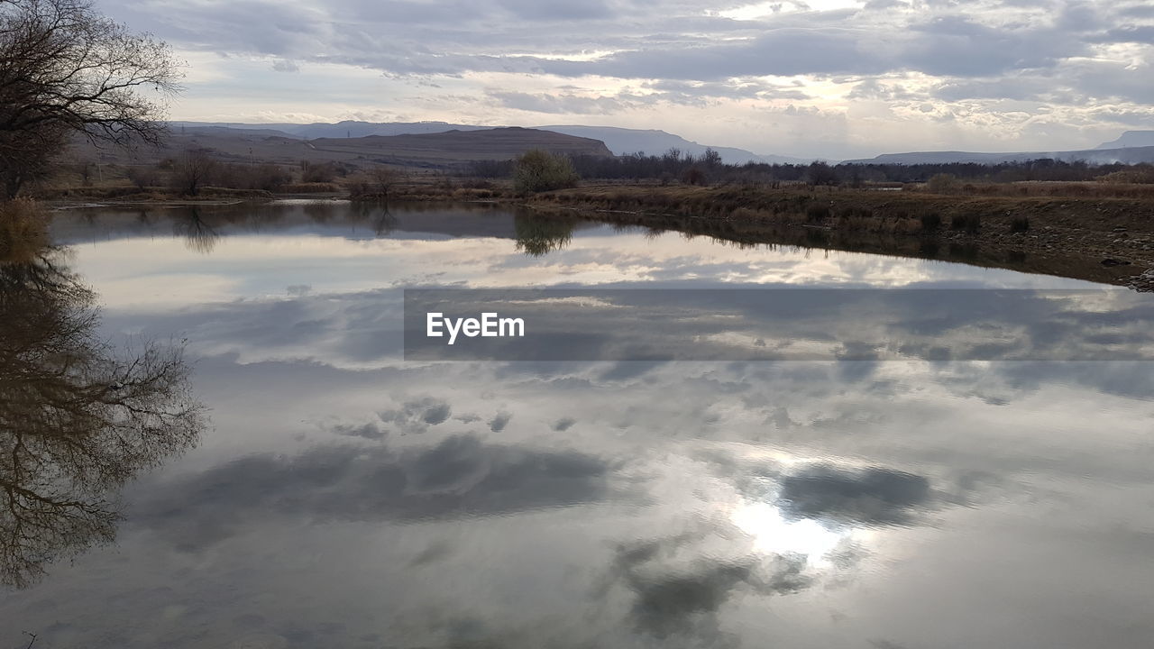 REFLECTION OF TREES IN LAKE AGAINST SKY