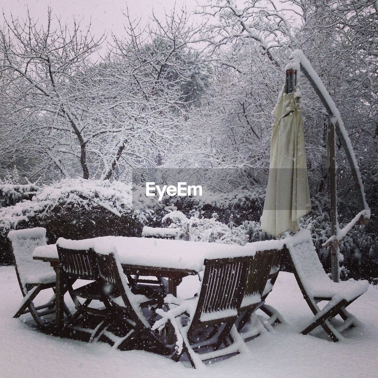 Snow covered chairs and tables in cafe