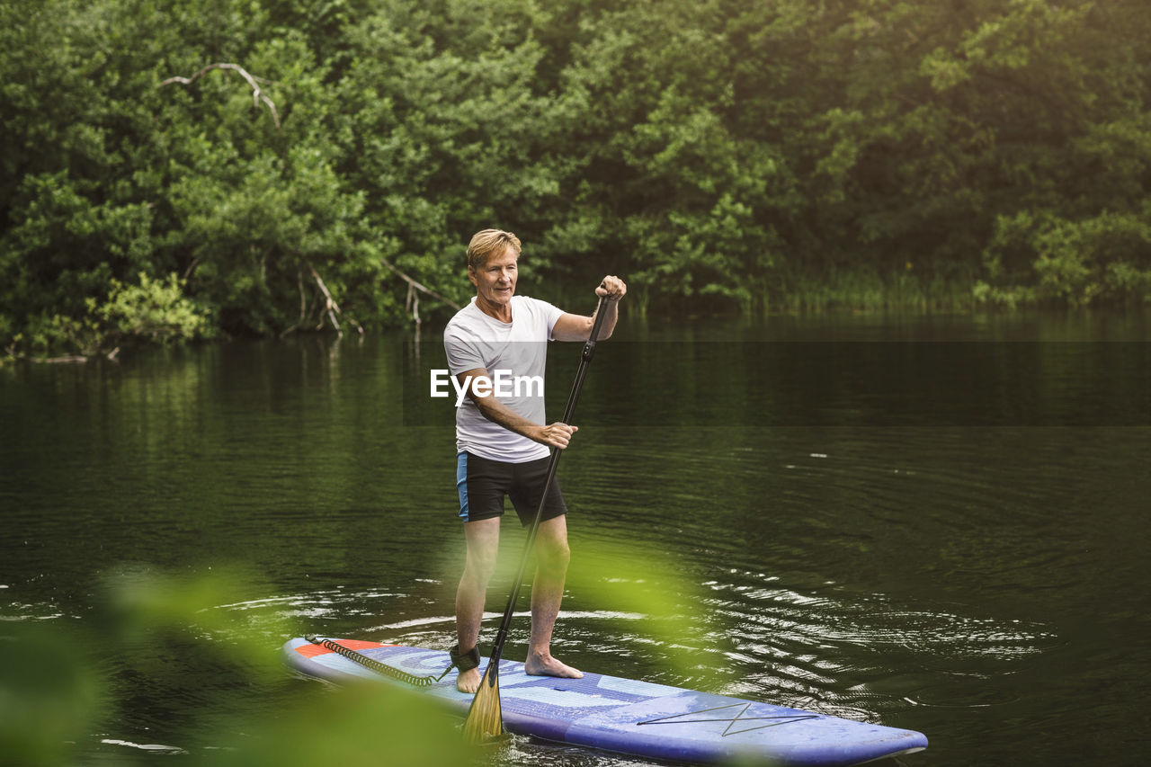 Senior man paddleboarding in sea during sup course