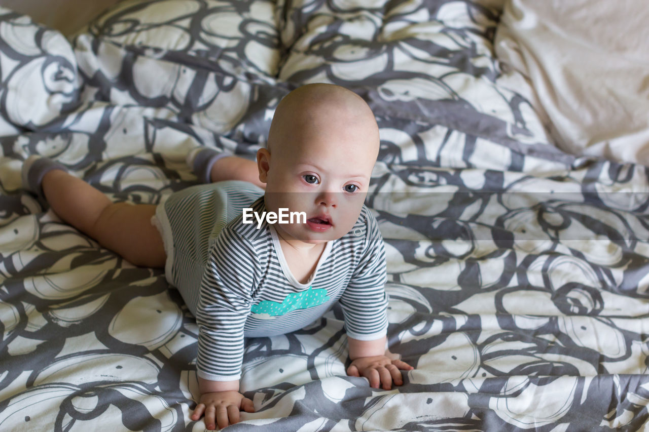 Cute baby boy lying on bed at home